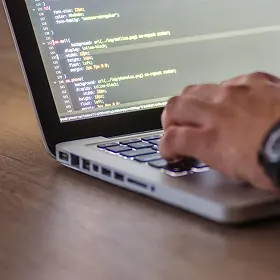 Korak 3 – Implementacija AI produkta v realnem okolju. Oseba piše programsko kodo na prenosnem računalniku.